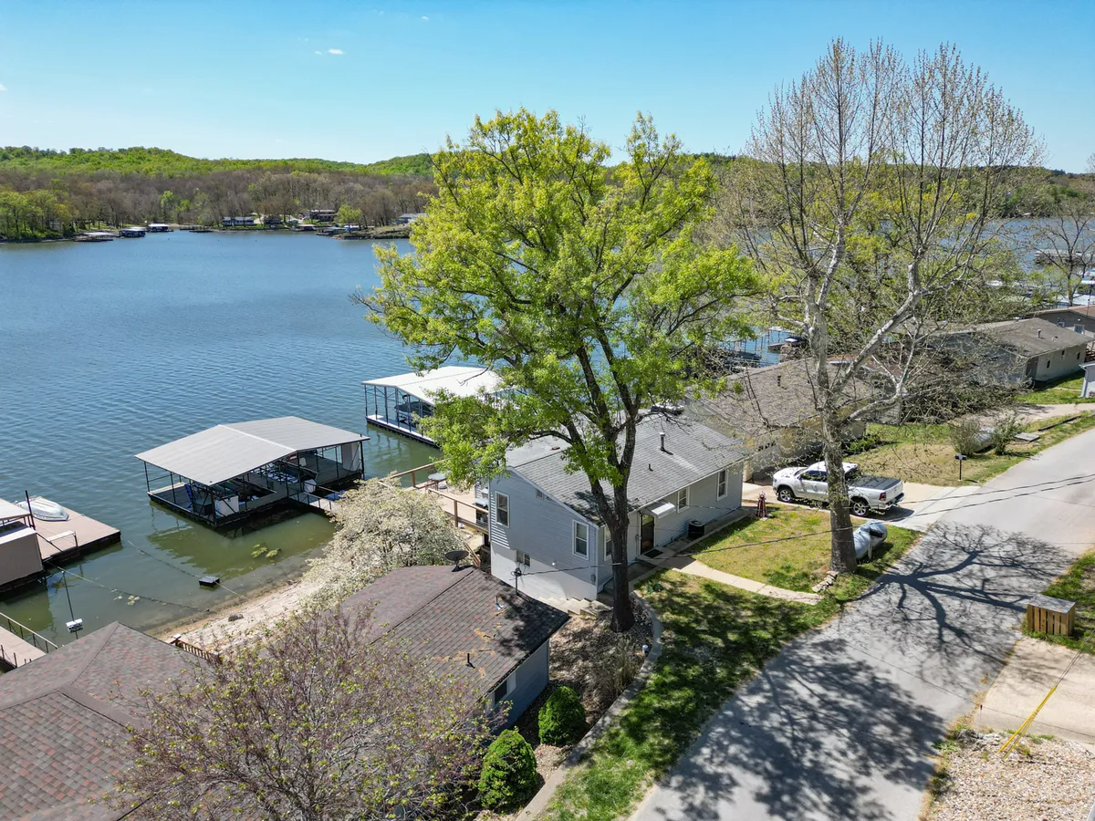 This image captures a tranquil view of the lake with dock structures, lush greenery, and residential buildings in the background. The scene suggests opportunities for outdoor activities such as boating, fishing, picnicking, and relaxing by the water, with peaceful sunset lighting that hints at both leisure and natural beauty.