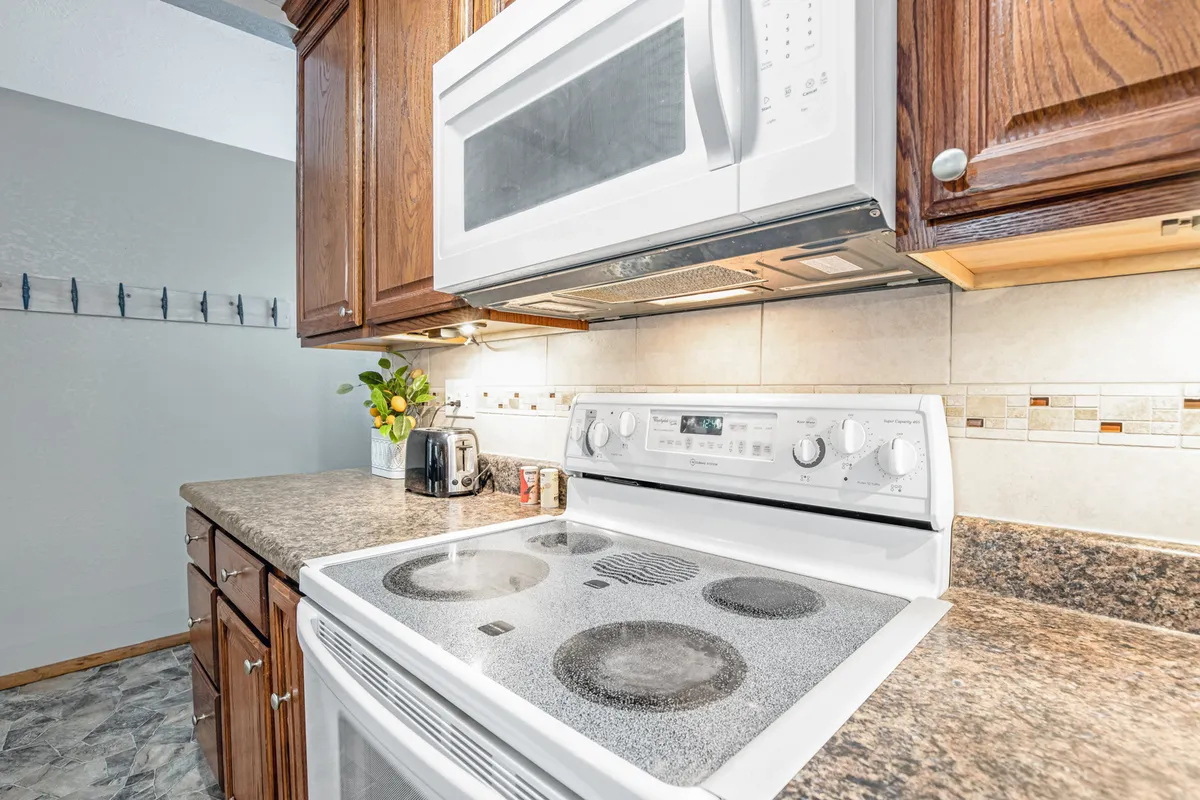 An inviting kitchen scene featuring modern appliances, ample counter space, and a central stove with a decorative flower arrangement. The setting is ideal for family cooking, with everything needed for meal prep easily accessible, reflecting the fully stocked kitchen described.